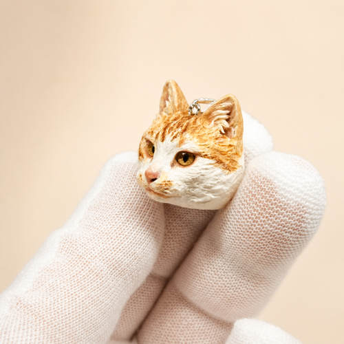 Custom orange and white cat clay necklace pendant, three-quarter view